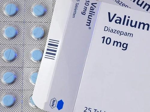 A close-up of a Valium 10mg medication package and several pills outside of the packaging.