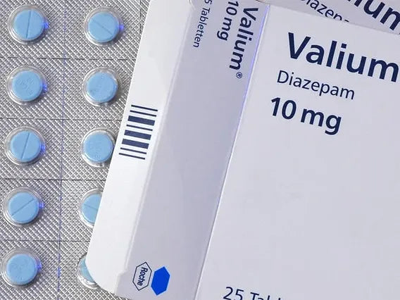 A close-up of a Valium 10mg medication package and several pills outside of the packaging.